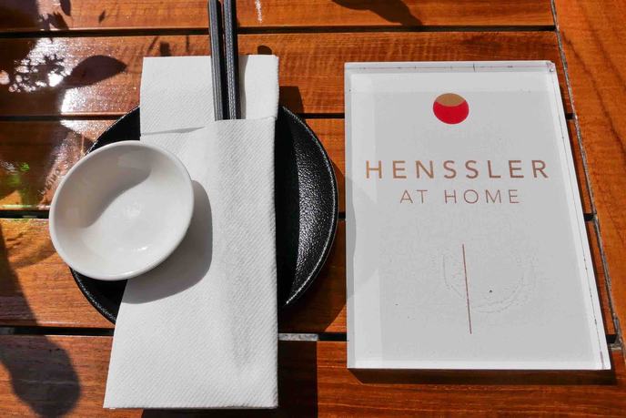 Gedeckter Tisch im Restaurant Henssler at Home mit Stäbchen, Teller und Speisekarte.