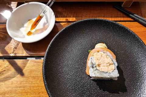 Sushi-Stück auf schwarzem Teller mit Sojasauce in Schale im Henssler at Home